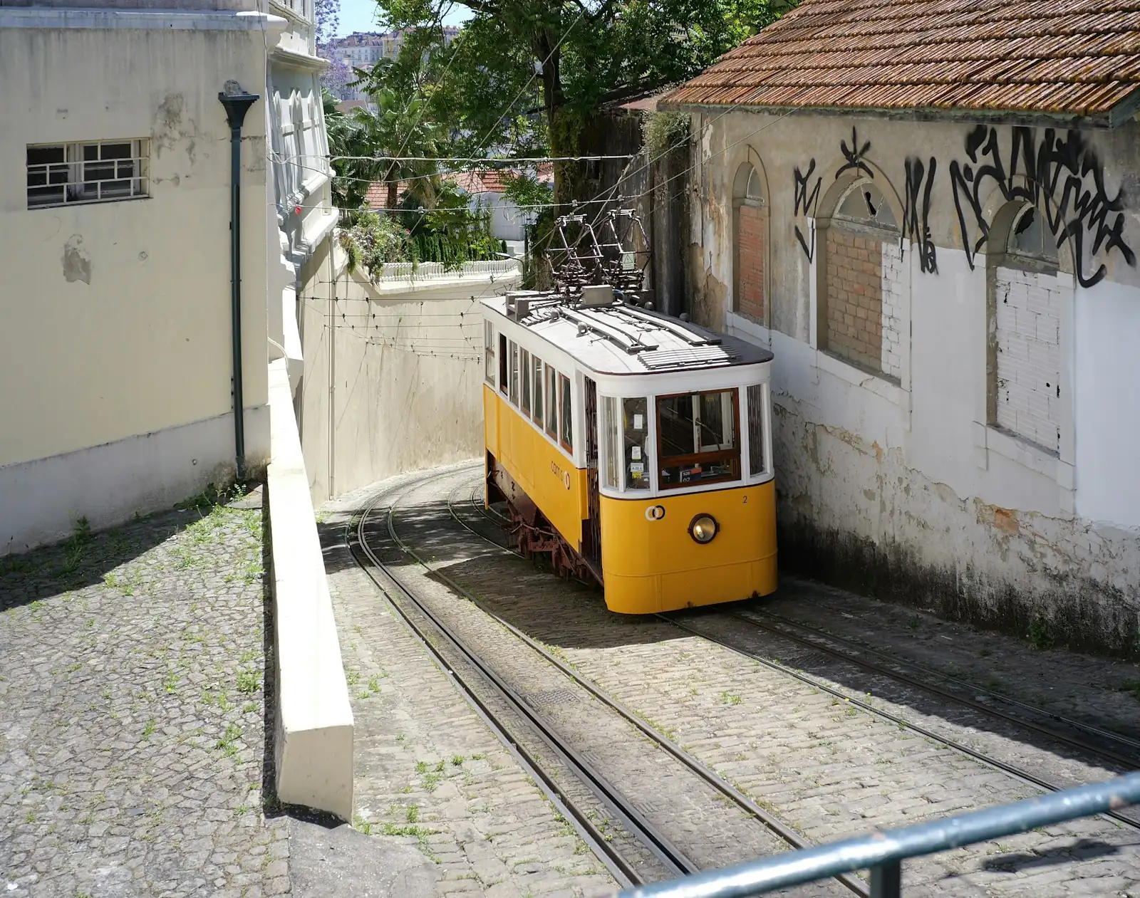Bonde amarelo subindo uma ladeira entre prédios