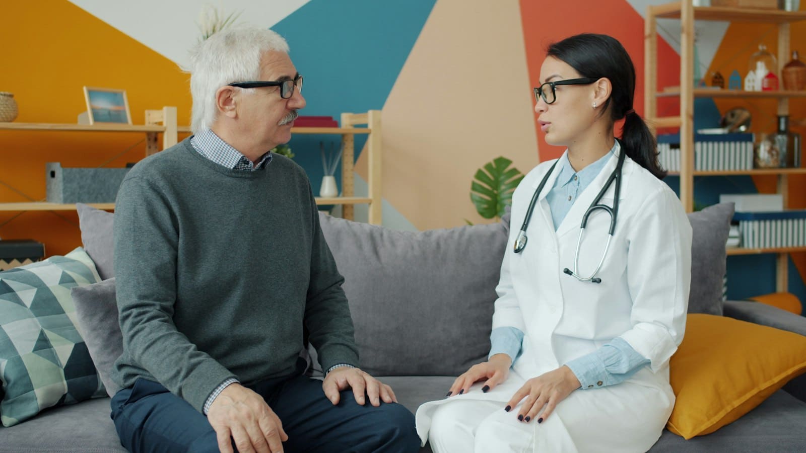 Remédios na bagagem de mão em viagem internacional: líquidos, controlados e receita em inglês 2 Médica com estetoscópio conversa com um senhor de cabelos brancos sentado no sofá do consultório